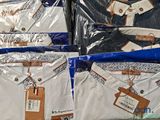 many shirts that are wrapped in plastic bags on the table