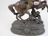 bronze statue of a man on a horse with a number plate on its back