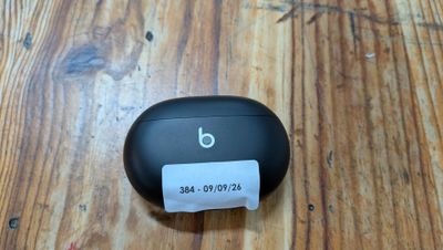 a small black object on a wooden table with a paper roll