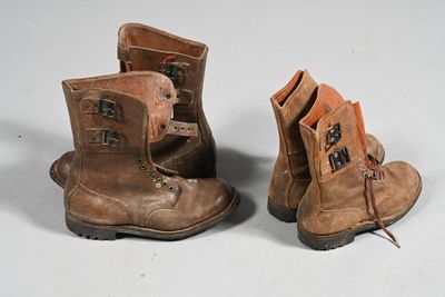 deux paires de bottes marron posées sur une surface blanche
