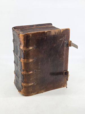an old leather book sitting on top of a white surface