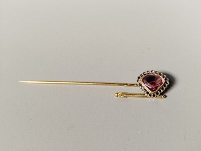 une photo d'une broche en or ornée d'une grenat en forme de cœur
