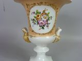 un vase blanc orné d'une anse dorée et d'un motif floral