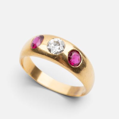a close up of a yellow gold ring with a diamond and ruby stones