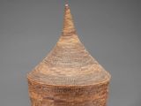 a large woven basket with a lid on a grey background