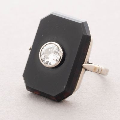 une image représentant une bague en diamant en noir et blanc posée sur une surface blanche
