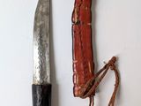 a knife and a leather sheath on a white surface