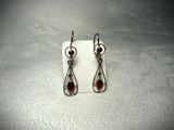a pair of earrings with garnets on them sitting on a white surface