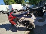 a red motorcycle parked in a parking lot next to a white van