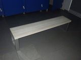 un banc au milieu d'une pièce, avec des casiers bleus en arrière-plan