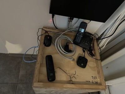 a wooden box with a phone, remote control, and other items on it