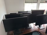 four computer monitors sitting on a desk in front of a window