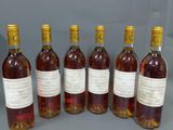 six bouteilles de vin sont alignées sur une table