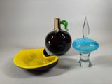three different colored glass objects sitting on a white surface