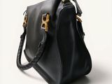 a black handbag with gold hardware on the handle and strap