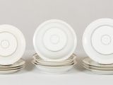 three white plates with silver rims sit on a white surface