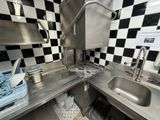 a kitchen with a sink, stove, and a checkered wall