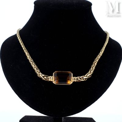 the necklace is made of gold and has a brown stone on it