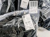 many bags of black clothing sitting on a table