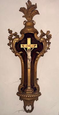 une croix accrochée au mur, sur laquelle est fixé un crucifix