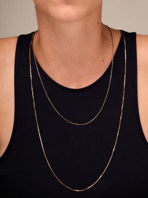 a woman wearing a black tank top and a gold chain necklace