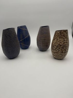 five vases that are lined up on a white surface