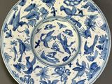 une assiette bleue et blanche décorée d'oiseaux et de fleurs, posée sur une table