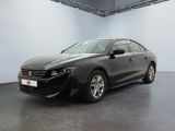 La voiture noire est garée dans une grande pièce aux murs blancs.