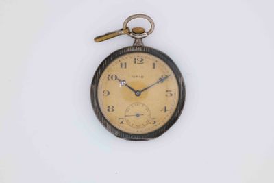 an old pocket watch hanging on a white wall