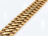 gros plan d'un bracelet en chaîne en or sur une surface blanche