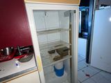un réfrigérateur vide dans une cuisine aux murs rouges