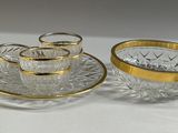 three glass cups and saucers on a plate with gold rims