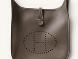 hermes logo on the front of a brown leather handbag