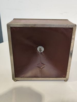 une horloge marron posée sur une table, sur fond blanc