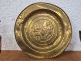 a gold plate sitting on a wooden table next to a silver cup