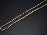 un collier de perles avec un fermoir en or sur fond noir