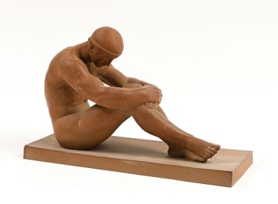 statue d'un homme assis sur un socle en bois, les mains posées sur les genoux