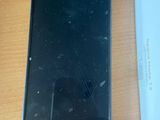 a black cell phone sitting on a table next to a charger