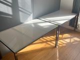 une table blanche avec un plateau en verre, posée sur un parquet en bois massif