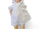 une poupée qui porte une robe blanche et un chapeau