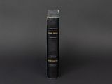 a black book sitting on top of a table next to a black wall
