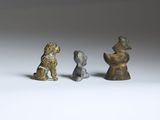 three bronze figurines of dogs and a cat on a white surface