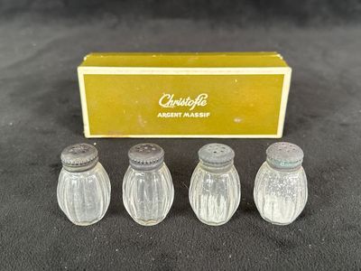 four glass salt and pepper shakers in a box on a table