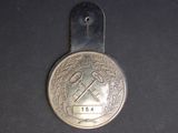 a silver medal with a hammer on it on a black surface