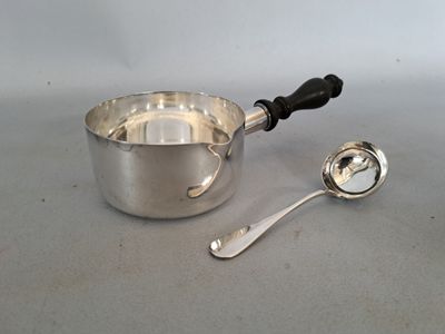 une casserole en argent et une cuillère posées sur une table