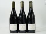 three bottles of wine are lined up on a white surface