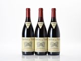 three bottles of red wine sitting on top of a white table