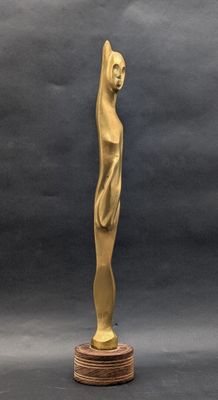 une statue en or représentant une femme debout sur un socle en bois