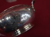 someone is holding a silver cup with a handle in their hand