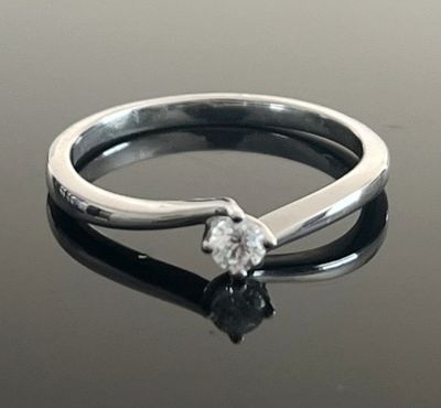 une bague en argent sertie d'un diamant, posée sur une table